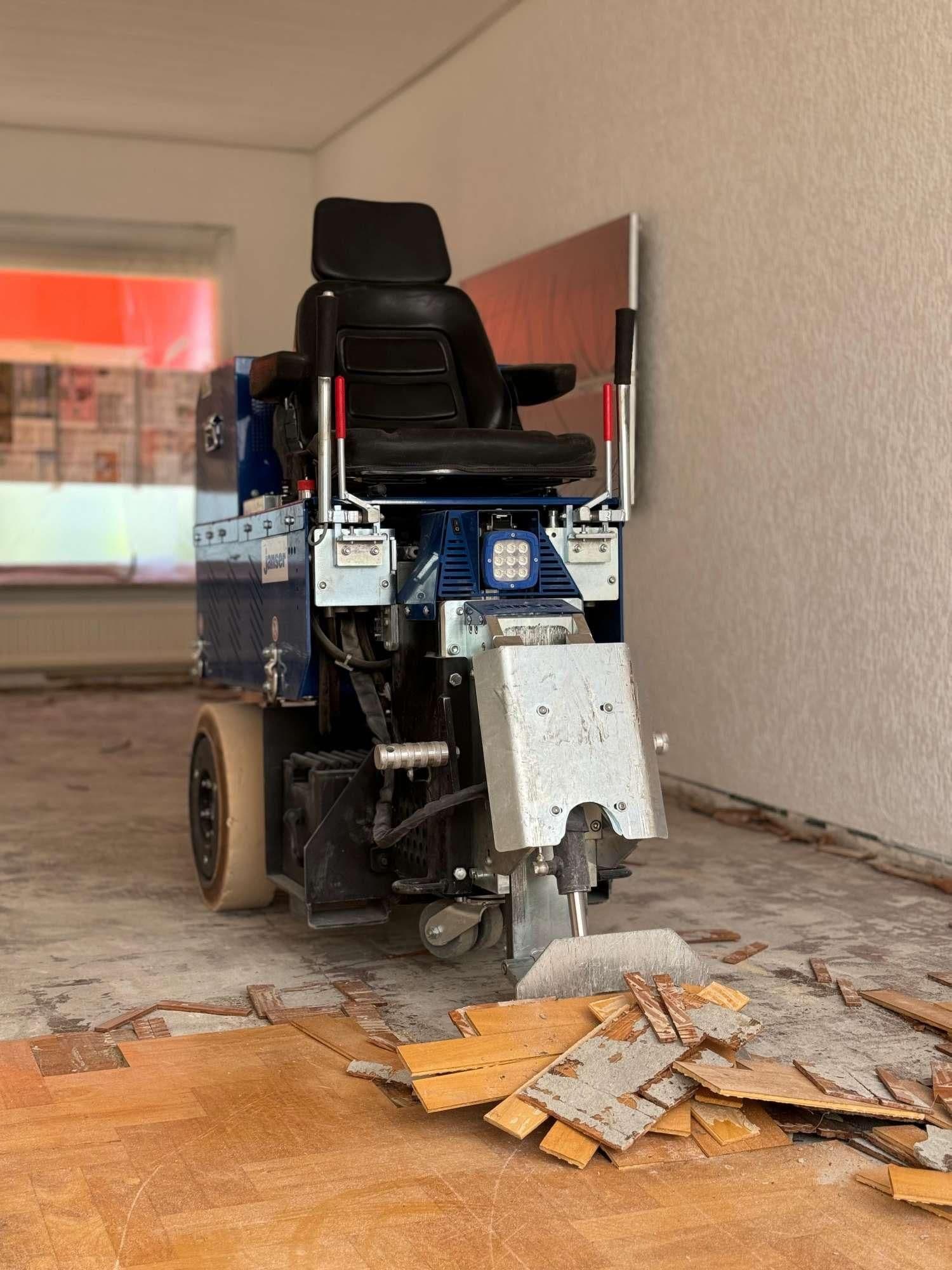 Machine met zwarte stoel voor het verwijderen van houten vloerplanken in een kamer